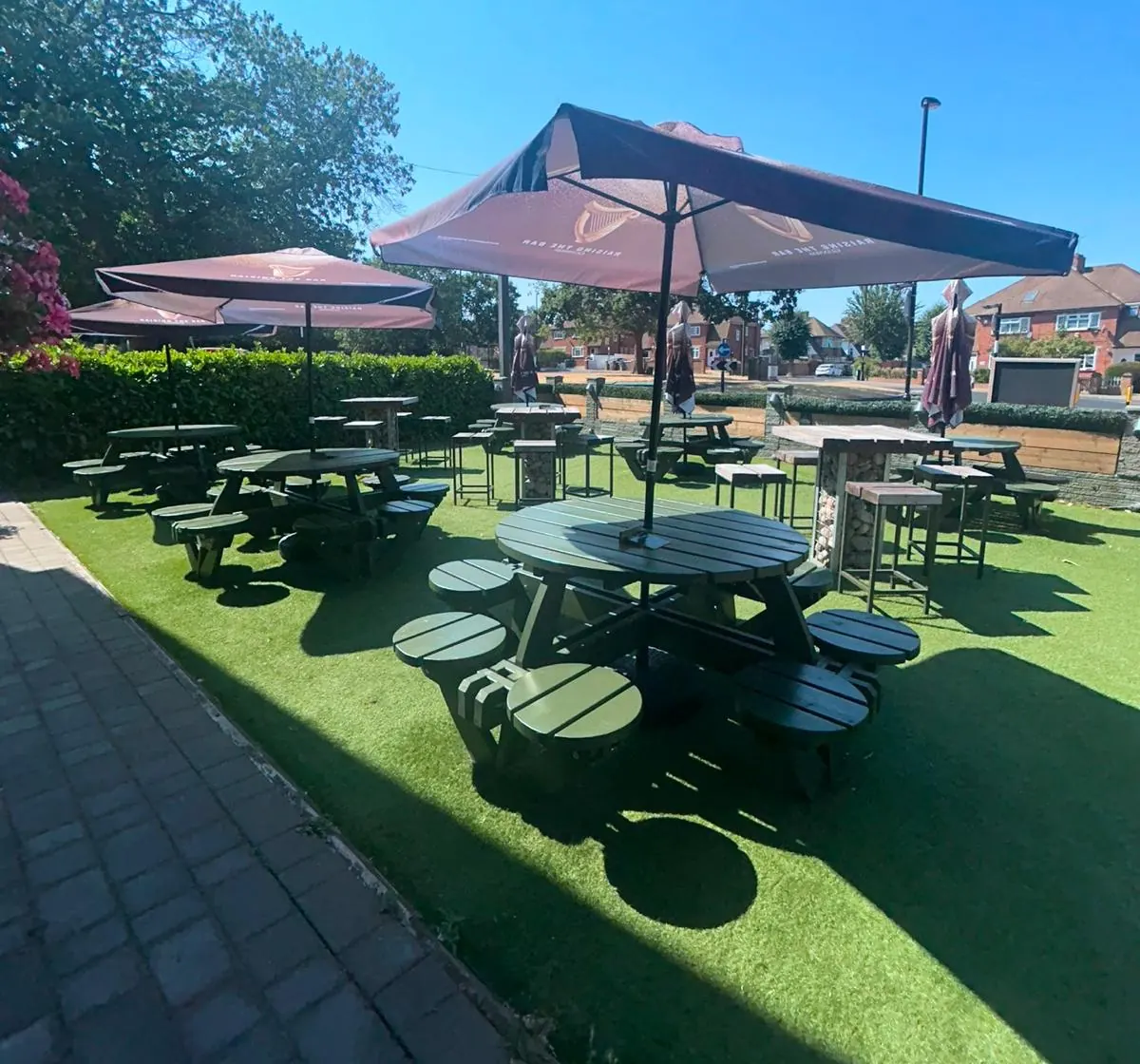Round picnic benches under parasols, with hedges behind