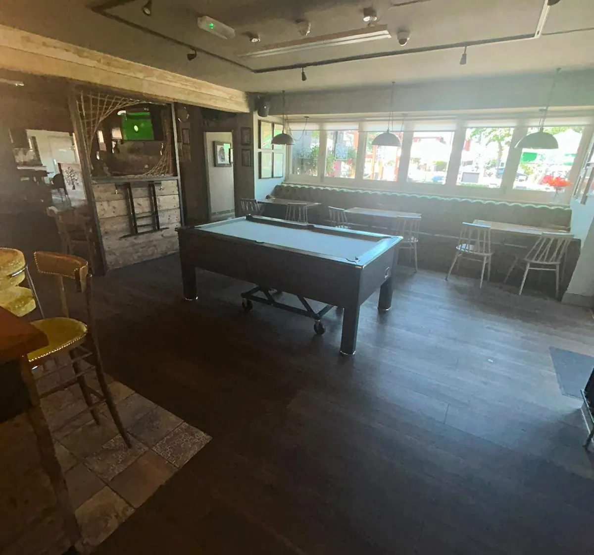 The pool table by the windows, with bench seating along the wall